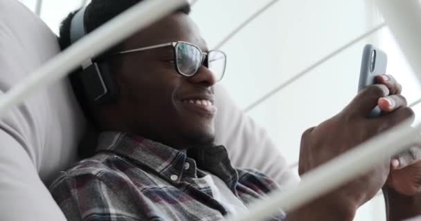 Hombre usando el teléfono móvil y escuchando música en los auriculares — Vídeos de Stock