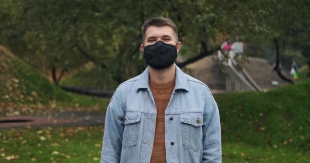 Hombre usando mascarilla protectora y saludando con dos dedos — Vídeo de stock