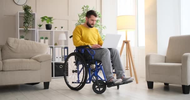 Hombre discapacitado en silla de ruedas trabajando con portátil — Vídeos de Stock