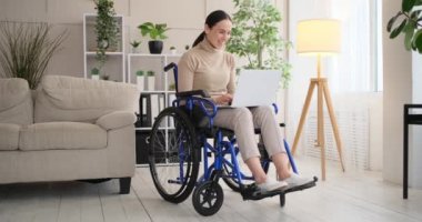 Tekerlekli sandalyede oturan engelli kadın dizüstü bilgisayarla çalışıyor.