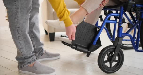 Sección baja del marido ayudando a la esposa a salir de la silla de ruedas — Vídeos de Stock