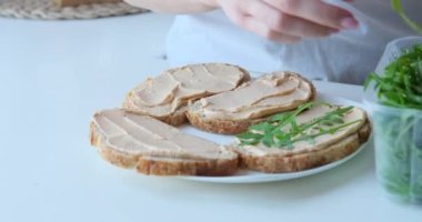 Kadın ekmek ve roka ile sandviç hazırlıyor.