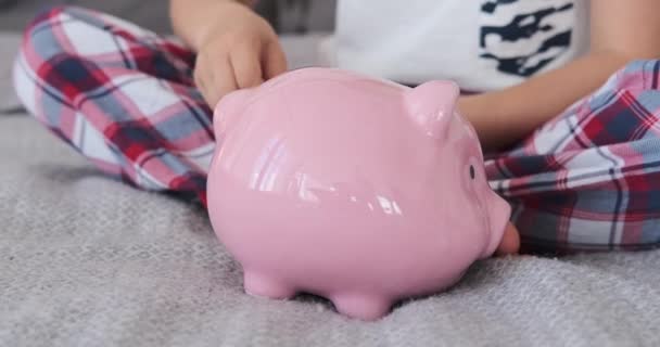 貯金箱にコインを挿入する少年 — ストック動画