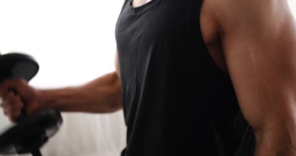 Mitten av människan gör biceps motion med hantlar i vardagsrummet — Stockvideo