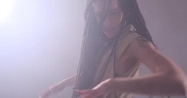 Uzun saçlı, arka planda dans eden ve sigara içen bir kadın.