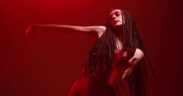 Kvinna med långt hår dansar i rött ljus och röker — Stockvideo