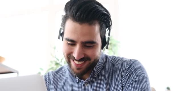 Молодий бізнесмен слухає музику і розважається перед ноутбуком — стокове відео