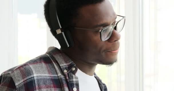 Homem feliz olhando pela janela enquanto ouve música em fones de ouvido — Vídeo de Stock