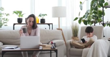 Oğlu cep telefonu kullanırken annesi evde çalışmakla meşgul.