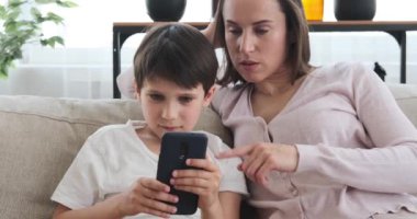 Anne ve oğlu evde cep telefonu kullanıyor.