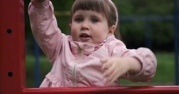 Malá holka lezení dolů opice bary v parku — Stock video