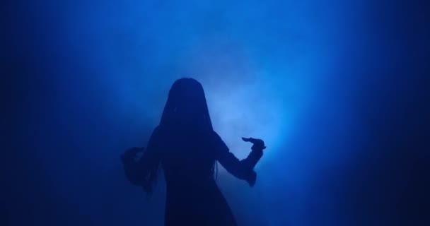 Sylwetka kobiety tańczącej w niebieskim świetle i dymie — Wideo stockowe