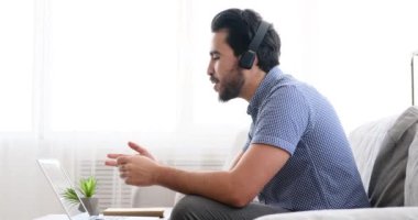 Kanepede oturan kulaklıkla iş adamı videosu konferansı.