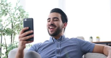 Genç adam cep telefonu kullanarak görüntülü konuşma yapıyor.
