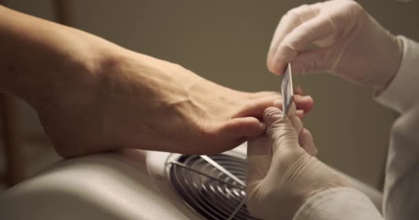 Pedicurista dando forma a las uñas de los pies de la mujer con una lima — Vídeo de stock
