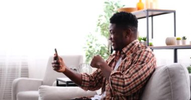 Heyecanlı genç adam cep telefonuyla görüntülü konuşma.