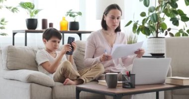 Çocuk telefonu kullanıyor ve annesinin işini bölüyor.