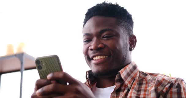 Afro-americano divertirsi mentre messaggistica di testo sul telefono cellulare — Video Stock