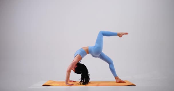 Ung kvinna som övar eka pada urdhva dhanurasana yoga pose — Stockvideo