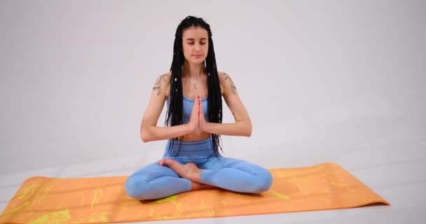 Jovem mulher meditando em posição de lótus com as mãos unidas — Vídeo de Stock