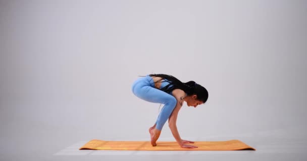 Junge Frau praktiziert Bakasana und Vrksasana Yoga-Pose — Stockvideo