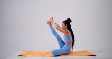 Janu sirsasana yoga pozu veren genç bir kadın.