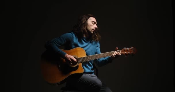 Young man playing guitar sitting on stool — Stock Video