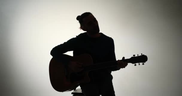 Silhouetteの若い男の演奏ギター — ストック動画