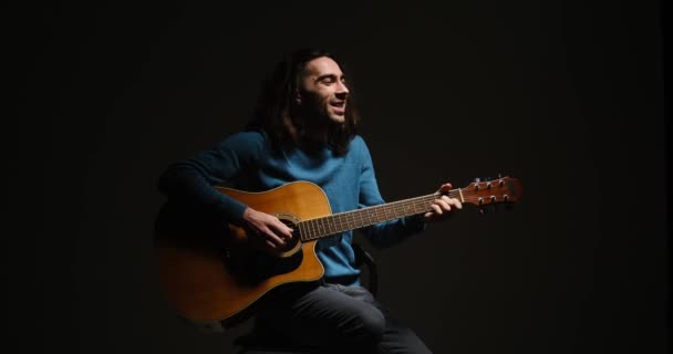 Νεαρός που τραγουδάει και παίζει κιθάρα καθισμένος σε σκαμπό — Αρχείο Βίντεο
