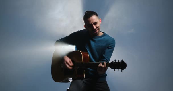 Selbstbewusster junger Mann singt und spielt Gitarre