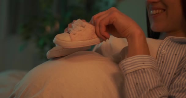 Lycklig kvinna gå baby skor på sin gravida mage hemma — Stockvideo