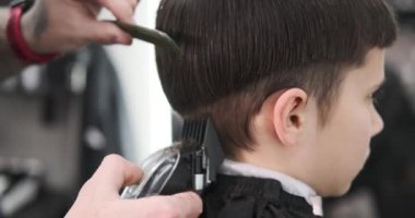 Çocuk berber dükkanında saçını kestiriyor.