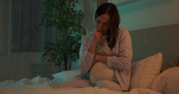 Mujer embarazada preocupada sentada en la cama en casa — Vídeo de stock
