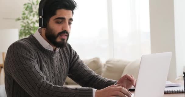 Бізнесмен насолоджується музикою на навушниках і працює на ноутбуці — стокове відео