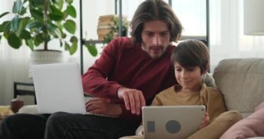 Bilgisayarda çalışan bir adam ve dijital tablet kullanan bir çocuk.