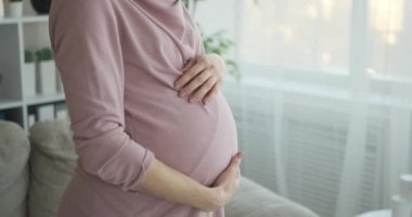 Hamile kadın beline dokunuyor ve esniyor.