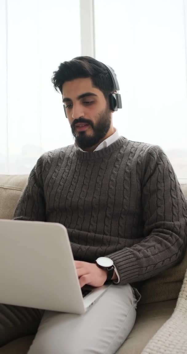 Ευτυχισμένος άνθρωπος ακούει μουσική στα ακουστικά και εργάζεται σε φορητό υπολογιστή — Αρχείο Βίντεο