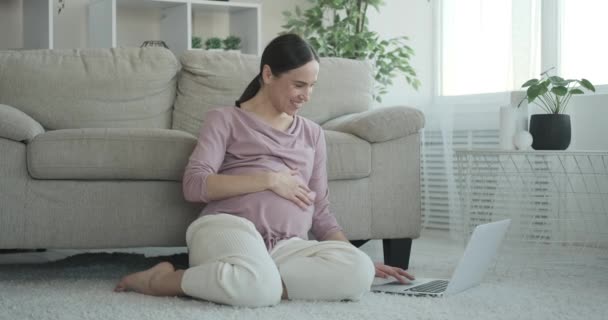 Pregnant woman using laptop on carpet at home — Stock Video