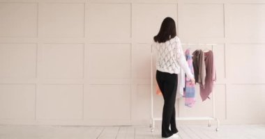 Kadın bütün giysileri raftan atıyor.