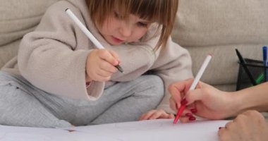 Anne ve kızı evde kağıda çizim yapıyor.