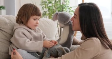 Anne ve kız el kuklası yumuşak oyuncaklarla oynuyorlar.