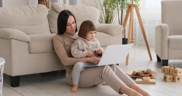 Córka siedzi z matką zajęta pracą na laptopie — Wideo stockowe