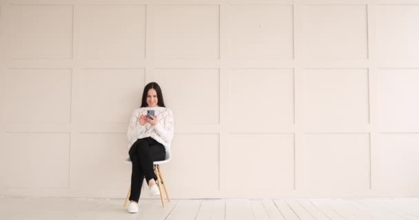 Mensajería de texto de mujer usando teléfono móvil sentado en la silla — Vídeos de Stock