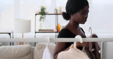 Giysileri askıdan seçen ve ceketi deneyen bir kadın.