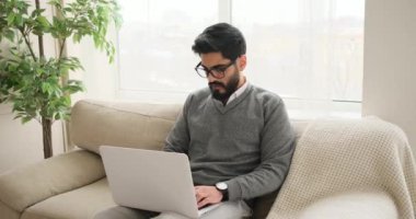 adam kanepede otururken dizüstü kullanarak