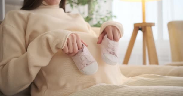 Mujer juguetona caminando zapatos de bebé en su vientre embarazada en casa — Vídeos de Stock
