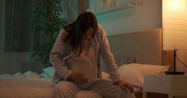 Pregnant woman suffering with pain on bed at night — Stock Video
