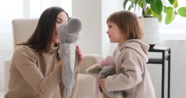 Anne ve kız el kuklası yumuşak oyuncaklarla oynuyorlar.