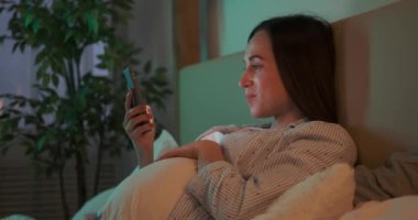 Hamile kadın evde cep telefonu kullanıyor.