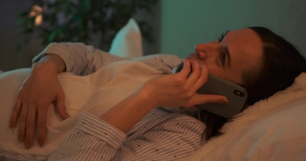 Mujer embarazada hablando por teléfono móvil acostada en la cama — Vídeos de Stock